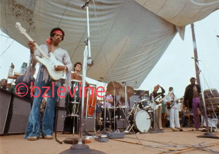Jimi Hendrix Band of Gypsies performing monday morning at Woodstock as featured (p26-27) in the Jimi Hendrix Live at Woodstock Alblum's 12x12 36 page Promotional book commemorating the 35Th Anniversary of Jimi's performance at the Woodstock Festival